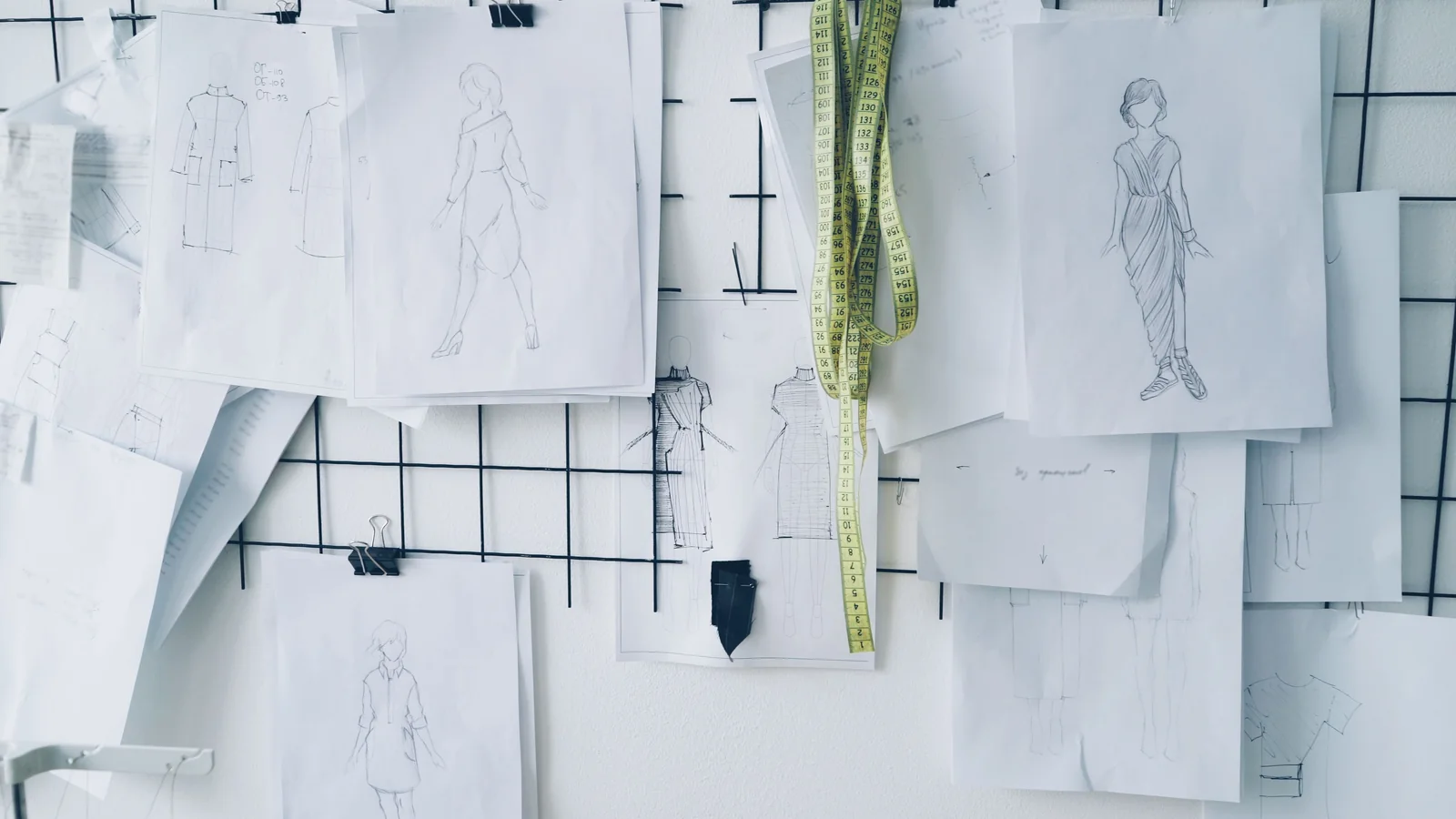 Fashion design sketches and a measuring tape on a workshop wall