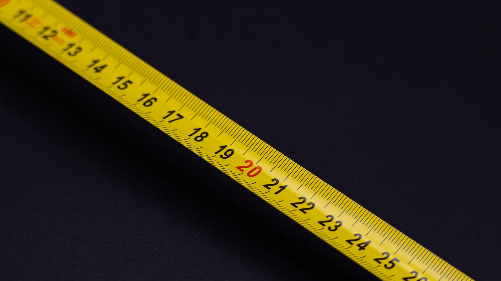 Close-up of a yellow measuring tape showing hat sizing measurements
